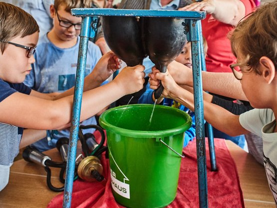 Kinder beim Melken eines Gummieuters