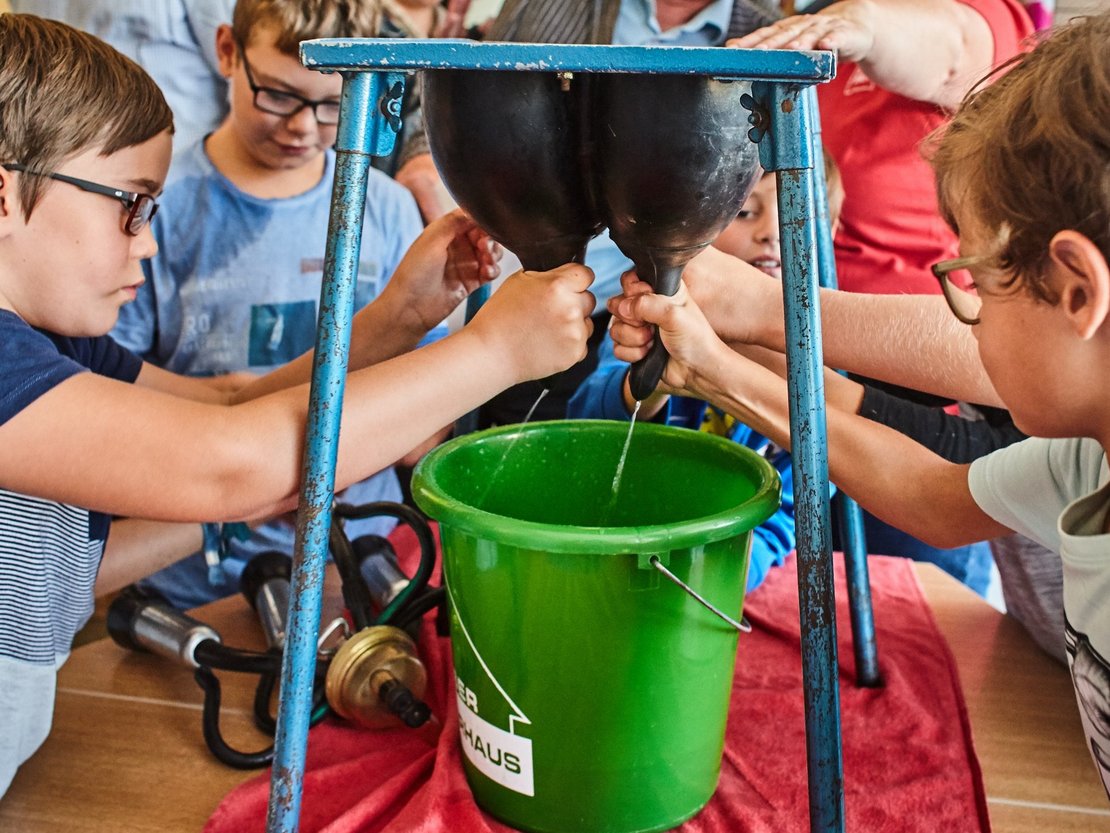 Kinder beim Melken eines Gummieuters