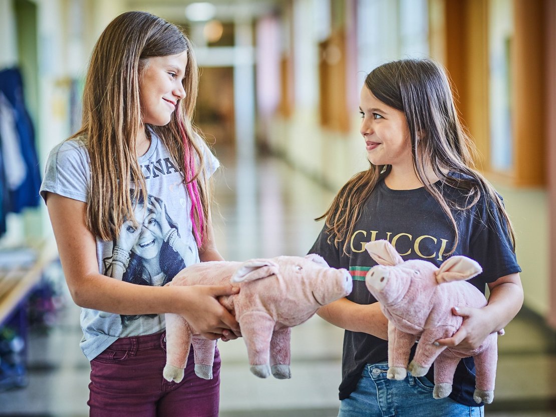 Kinder mit Spielschweinen in der Hand