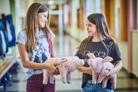 Kinder mit Spielschweinen in der Hand
